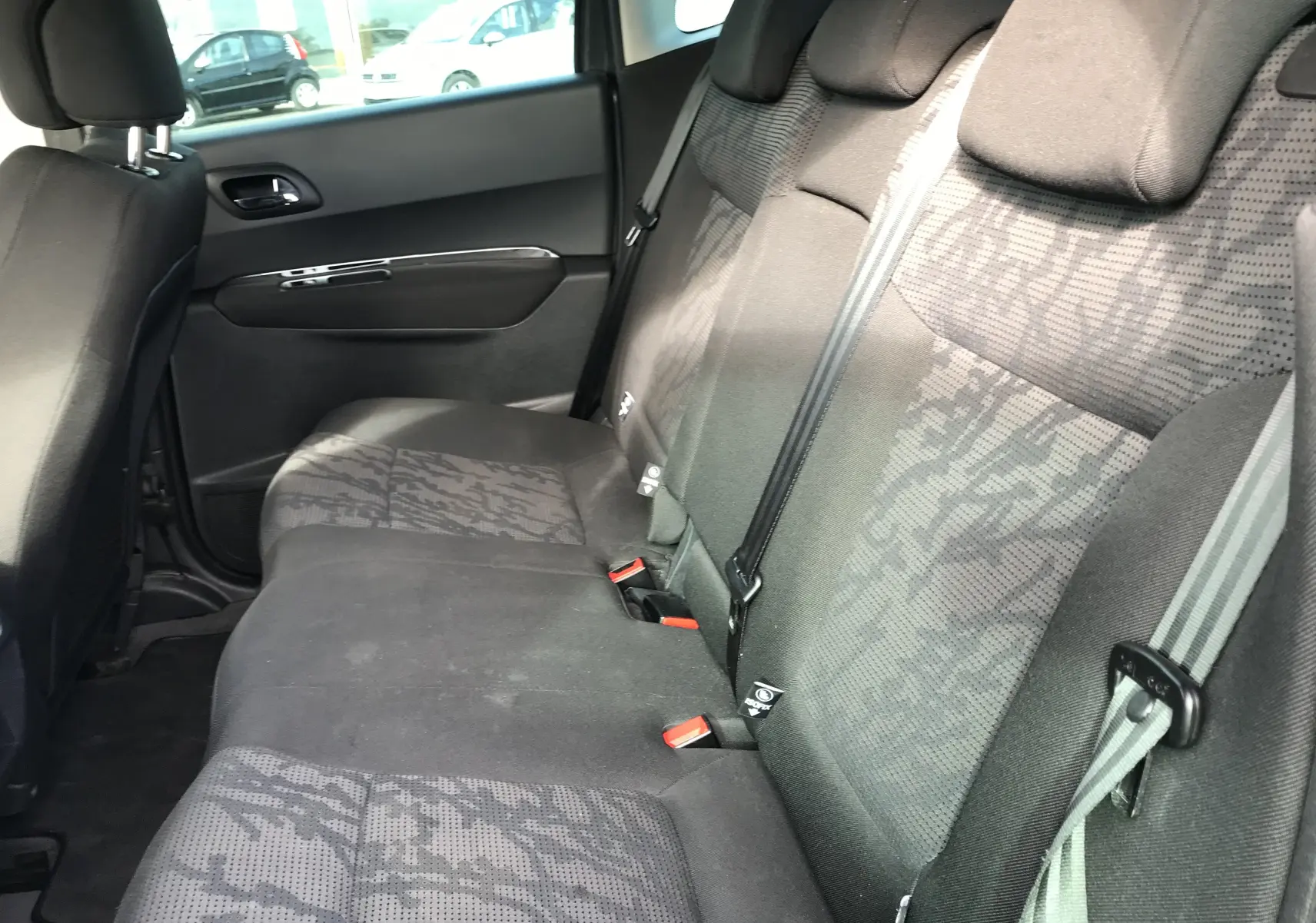 Vue intérieure côté droit des sièges arrière gris anthracite du Peugeot 3008 2011 avec ceinture de sécurité et appuie-têtes.
