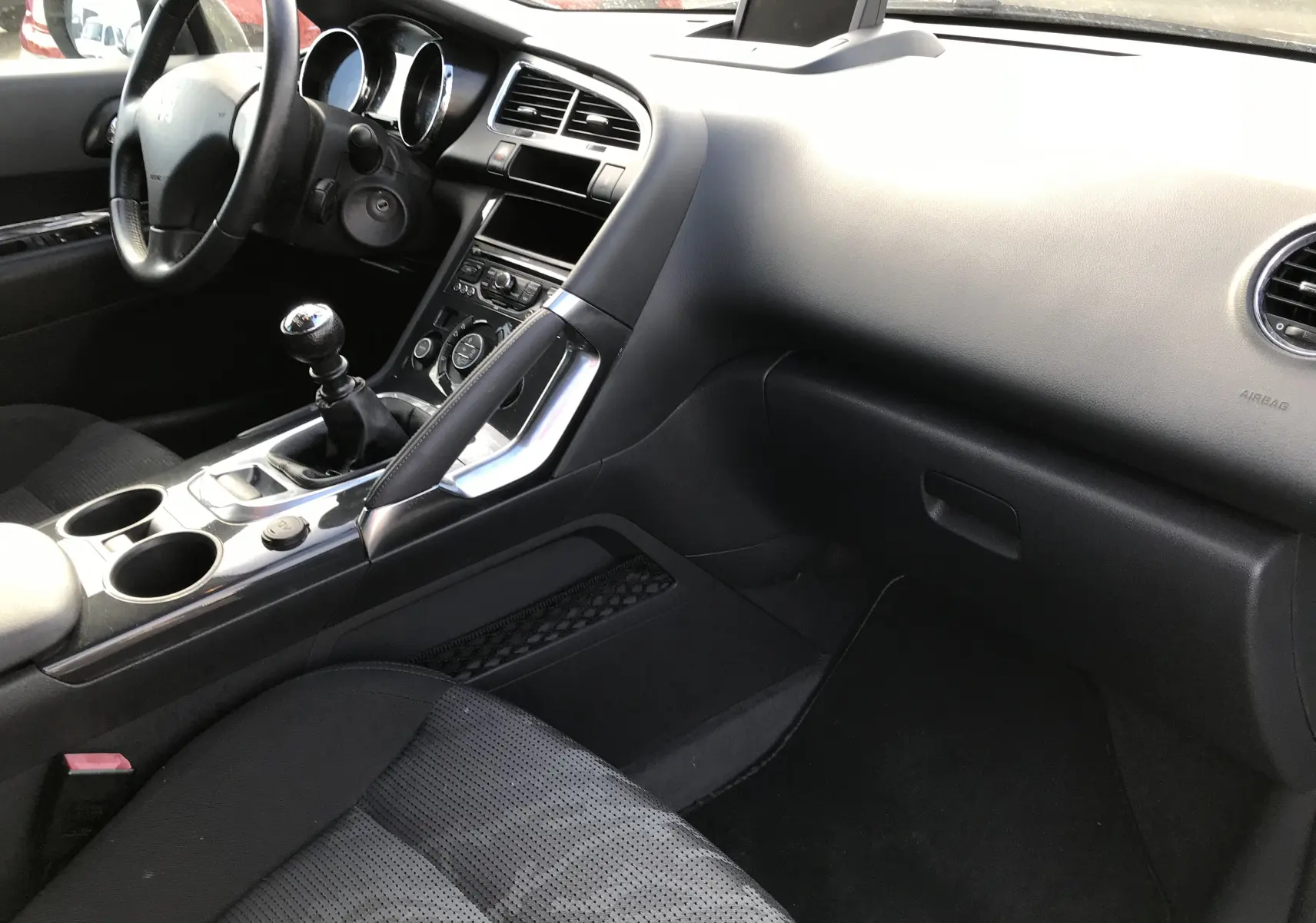 Intérieur noir du Peugeot 3008 2011, vue côté passager avec tableau de bord et levier de vitesse manuel visibles.