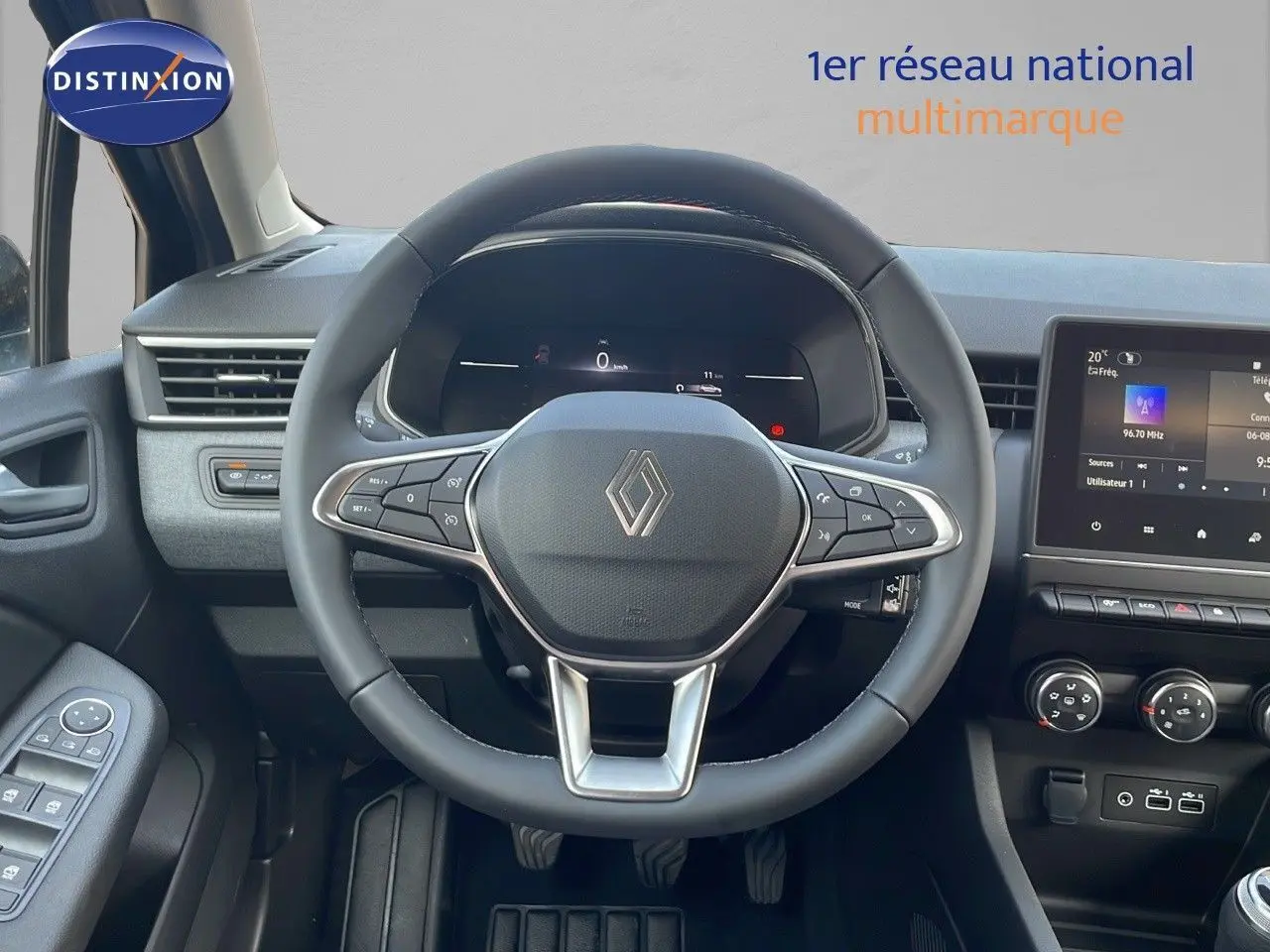 Vue intérieure centrée sur le volant noir d'une Renault Clio 2025 avec tableau de bord numérique et écran tactile.