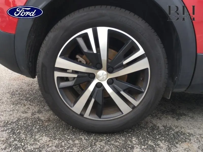 Gros plan sur la roue avant droite d'un Peugeot 3008 rouge Ultimate avec jante alliage bicolore design moderne.