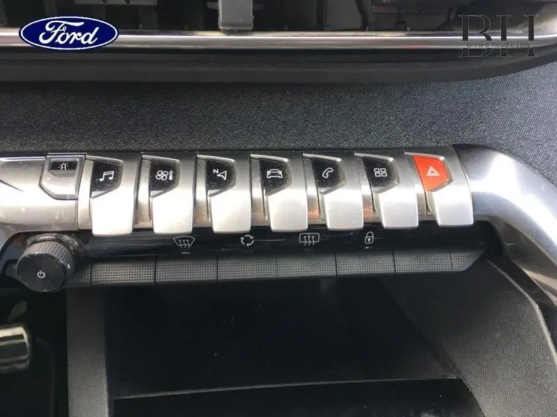 Gros plan sur les commandes centrales argentées du tableau de bord d'un Peugeot 3008 rouge Ultimate, avec bouton d'alerte rouge.