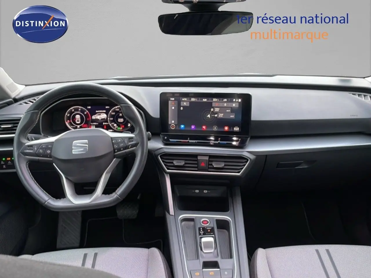 Vue intérieure du tableau de bord et volant du SEAT LEON ST gris urbain, avec écran tactile central et commandes modernes.