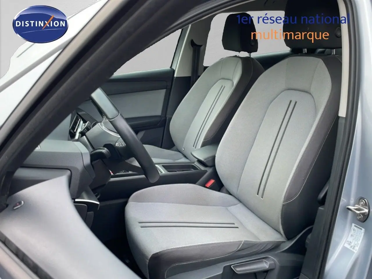 Vue intérieure côté conducteur du SEAT LEON ST 2022, sièges tissu gris clair avec détails sombres, ambiance épurée.