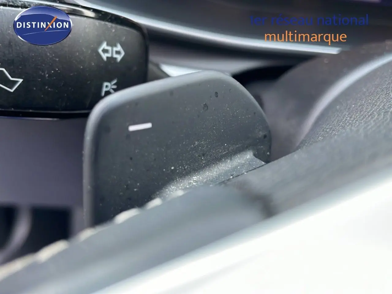 Gros plan sur la palette de changement de vitesse au volant d’une SEAT LEON ST gris urbain métal, intérieur noir.