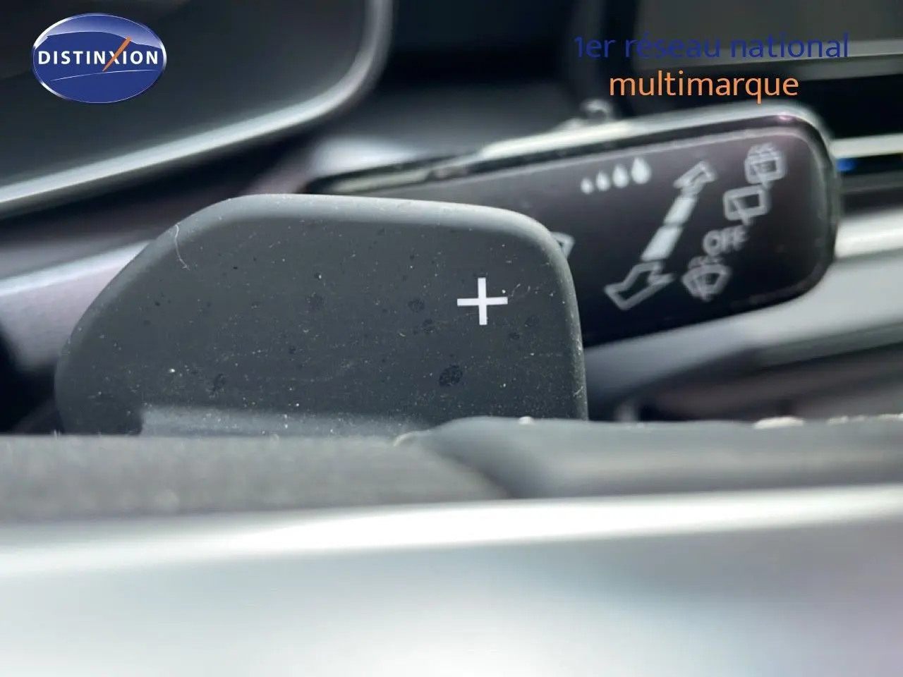 Gros plan sur la palette de changement de vitesse "+" côté droit dans l'habitacle d'une SEAT LEON ST gris urbain.