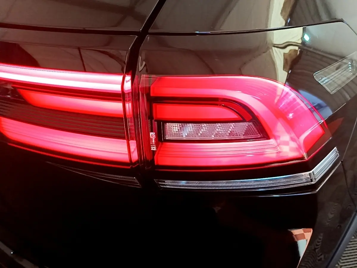 Gros plan sur le feu arrière droit rouge allumé du Volkswagen Taigo noir 2023, soulignant ses lignes LED distinctives.
