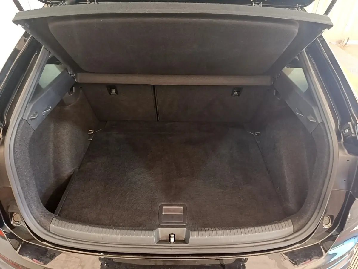 Coffre ouvert vu de l'arrière d'un Volkswagen Taigo noir 2023, espace de chargement vide et tapis noir.