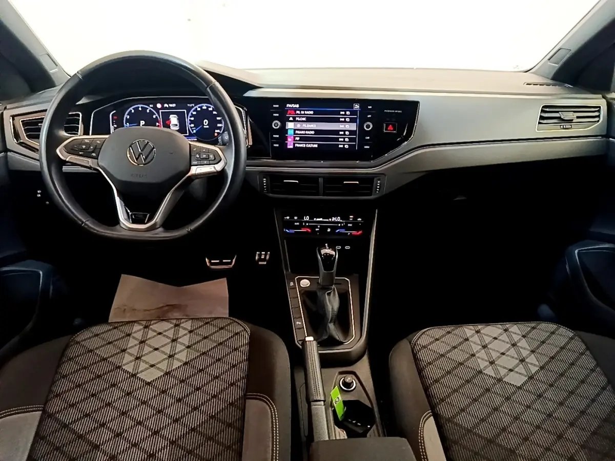 Vue intérieure avant du Volkswagen Taigo 1.5 TSI 150 DSG R-Line 2023, tableau de bord numérique et volant cuir noir.