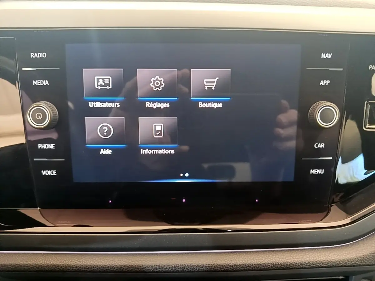 Écran tactile central du tableau de bord du Volkswagen Taigo noir, affichant le menu principal avec options utilisateurs, réglages et boutique.