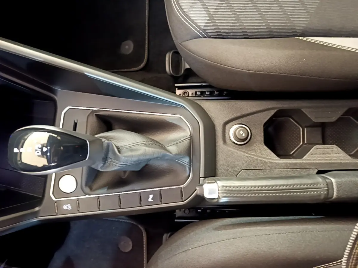 Vue rapprochée de la console centrale du Volkswagen Taigo noir 2023, avec levier de vitesse automatique et frein à main.