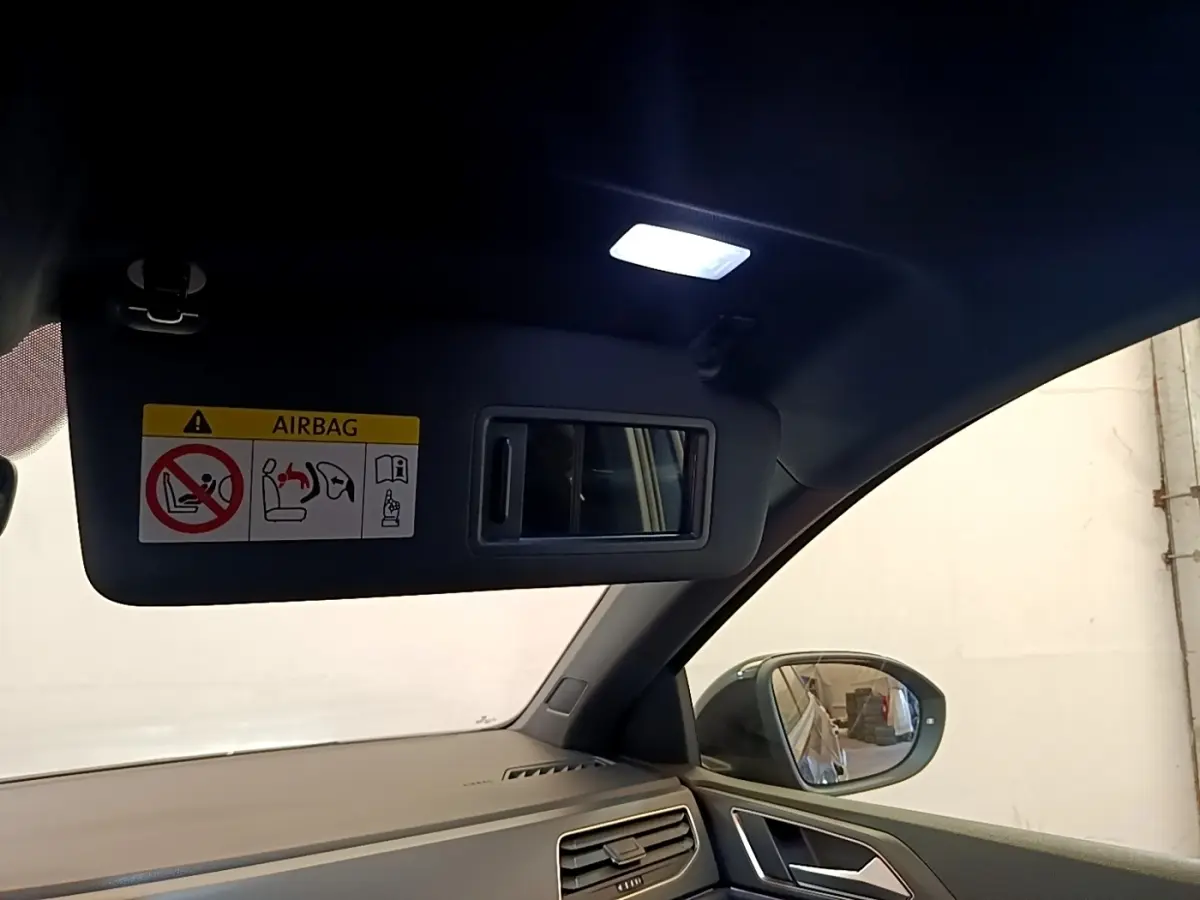 Vue intérieure côté conducteur du Volkswagen Taigo noir 2023, avec pare-soleil ouvert et miroir intégré éclairé.