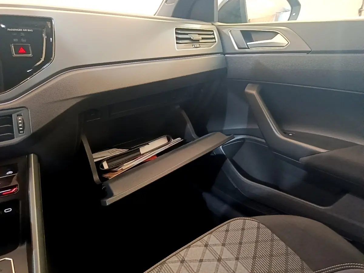 Intérieur côté passager du Volkswagen Taigo noir 2023, boîte à gants ouverte avec documents visibles.