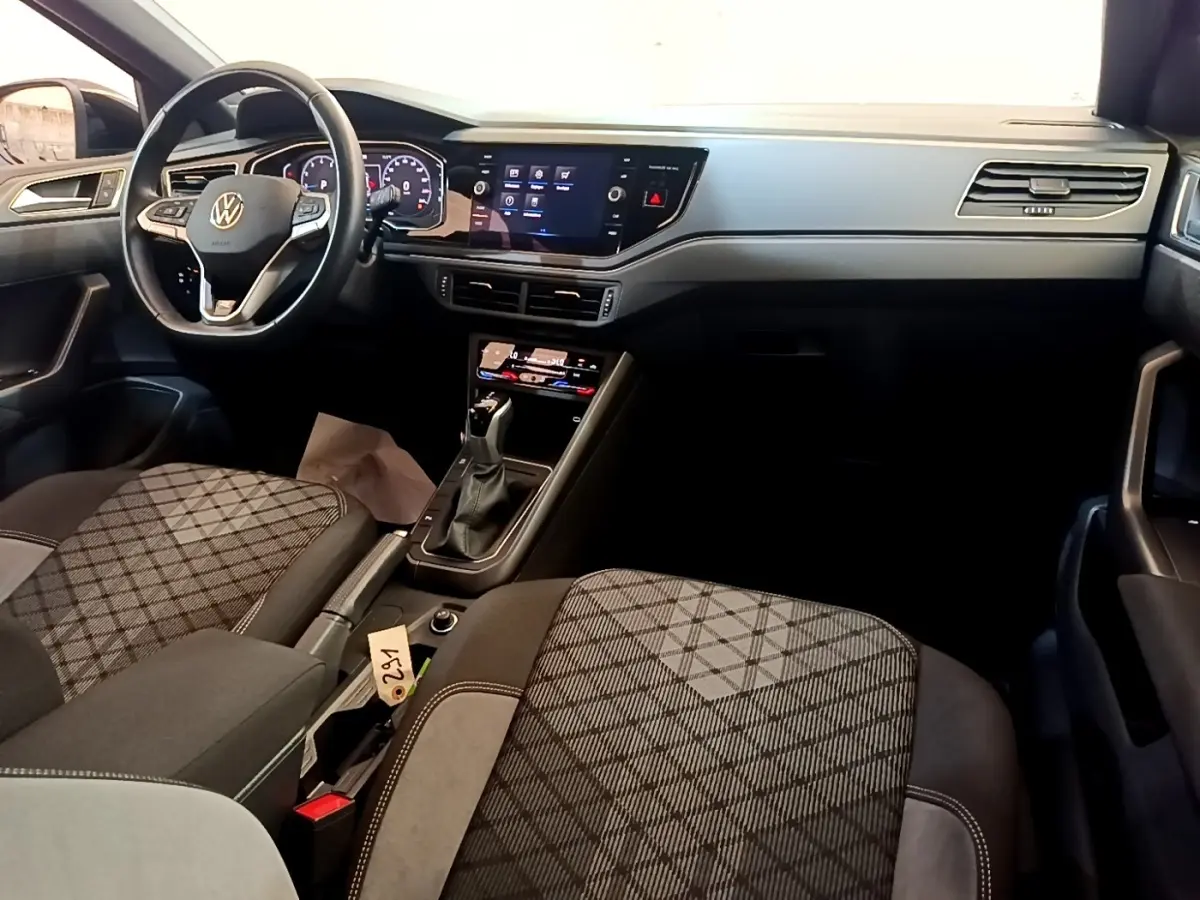 Vue intérieure avant droite du Volkswagen Taigo 1.5 TSI 150 DSG R-Line 2023, sièges tissu à motifs et tableau de bord digital.