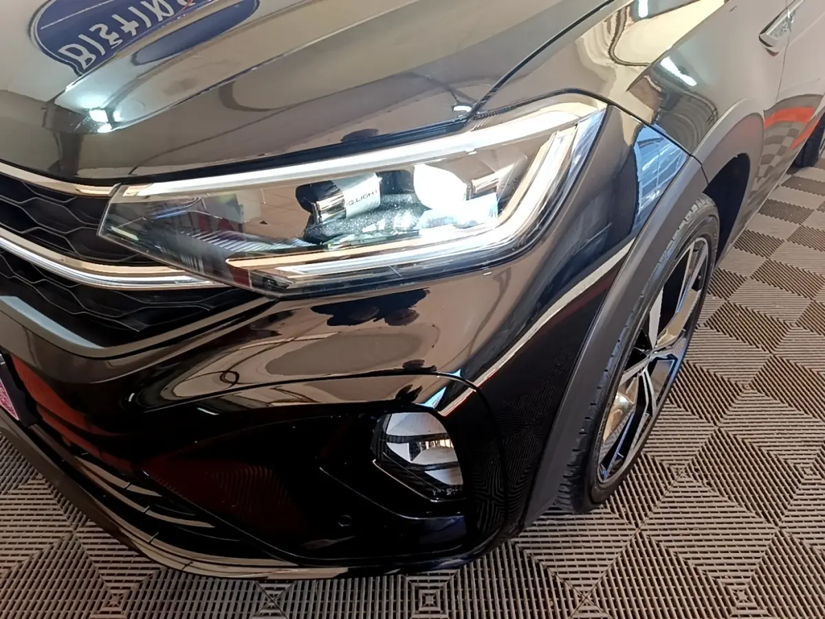 Gros plan sur l'avant droit noir brillant du Volkswagen Taigo 1.5 TSI 150 DSG R-Line avec phares LED et jante alliage.