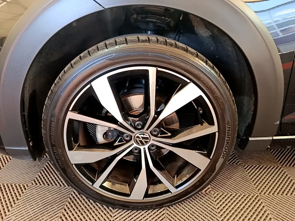 Gros plan sur la roue avant droite noire du Volkswagen Taigo 1.5 TSI 150 DSG R-Line avec jante alliage bicolore.