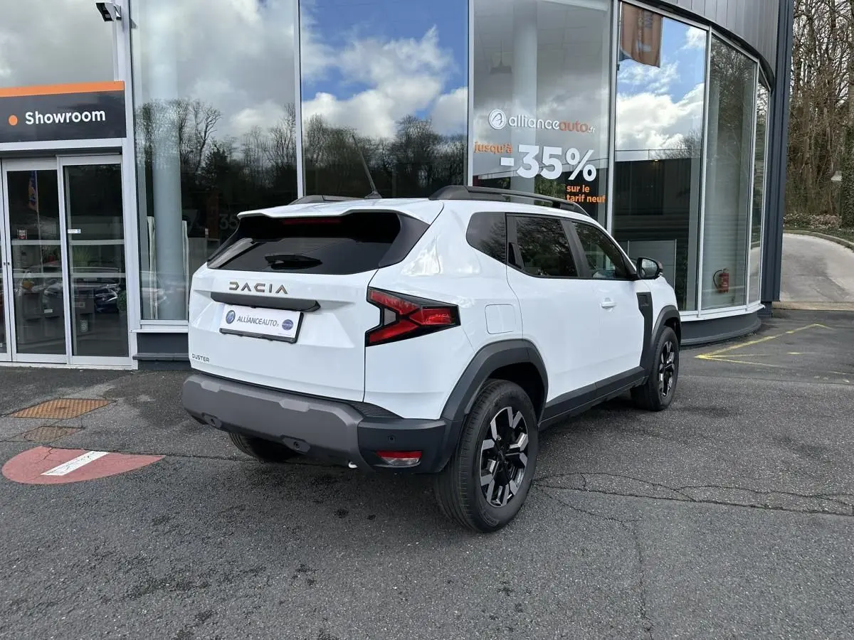 Vue 3/4 arrière droite du Dacia Duster blanc glacier avec jantes alliage noires et vitres surteintées.