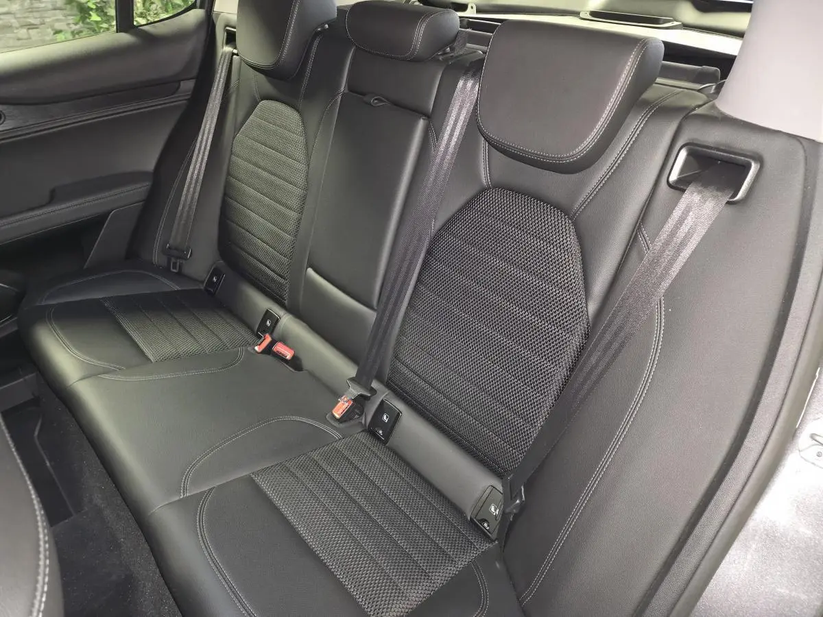 Vue rapprochée de la banquette arrière noire en tissu et cuir de l'Alfa Romeo Stelvio 2022, avec ceintures de sécurité visibles.