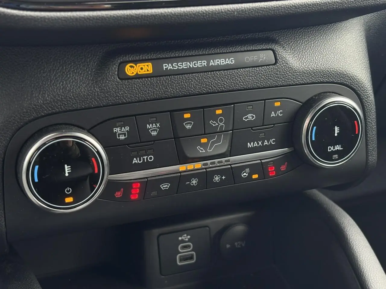 Vue rapprochée du tableau de bord du Ford Kuga 2023, montrant la climatisation automatique bi-zone et commandes chauffantes.