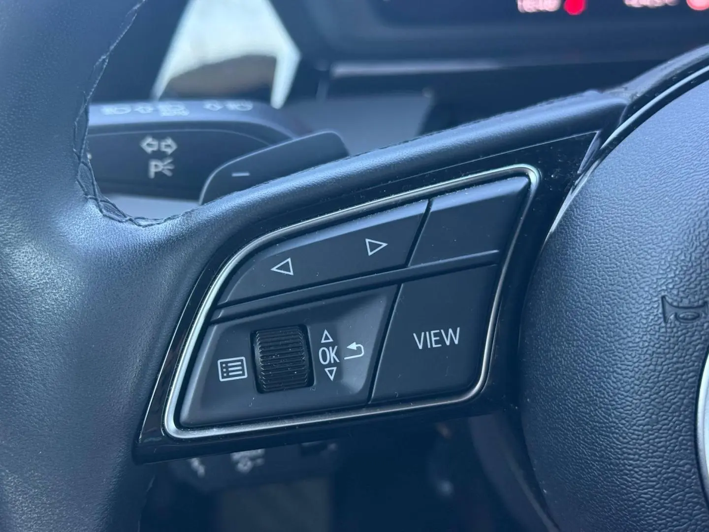 Gros plan sur les commandes multifonctions côté gauche du volant cuir de l'Audi A3 Sportback 2024.