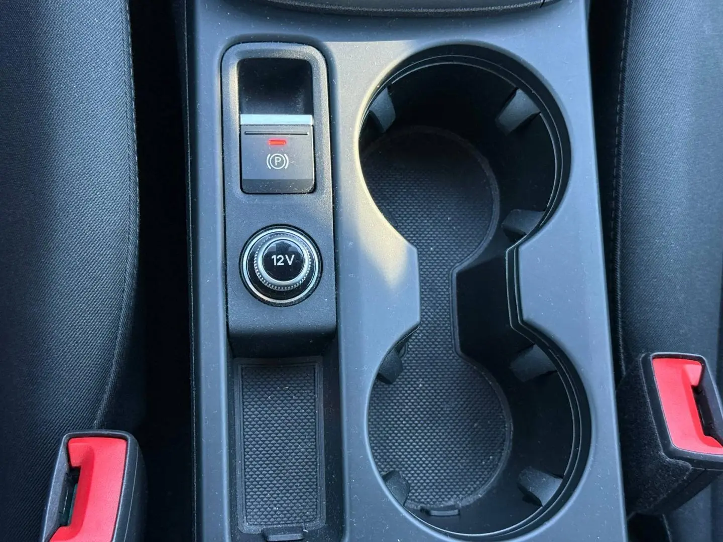 Gros plan sur la console centrale noire de l’Audi A3 Sportback 2024, avec porte-gobelets et bouton 12V visible.