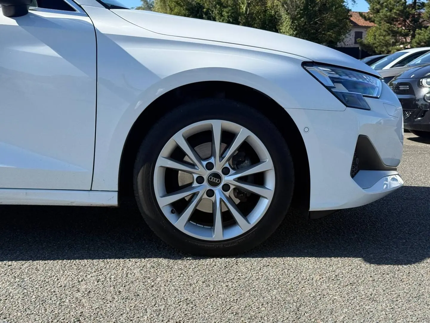 Gros plan sur la roue avant gauche et le pare-chocs avant blanc Arkona d'une Audi A3 Sportback 2024.