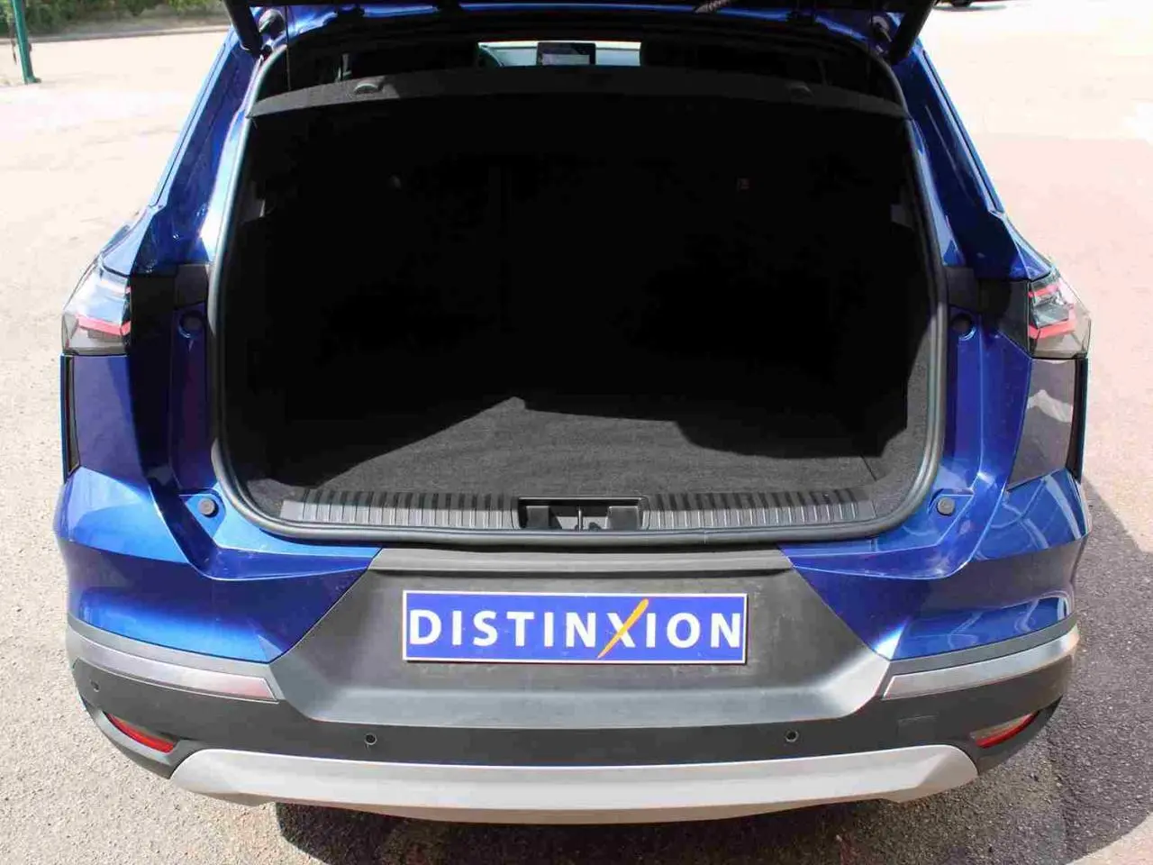 Vue arrière ouverte du coffre d’un Renault Symbioz bleu avec pare-chocs noir et plaque Distinxion.