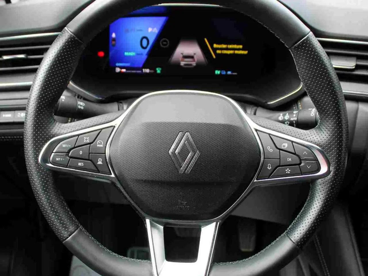 Vue rapprochée du volant noir perforé avec logo Renault et tableau de bord numérique du Renault Symbioz 2025.