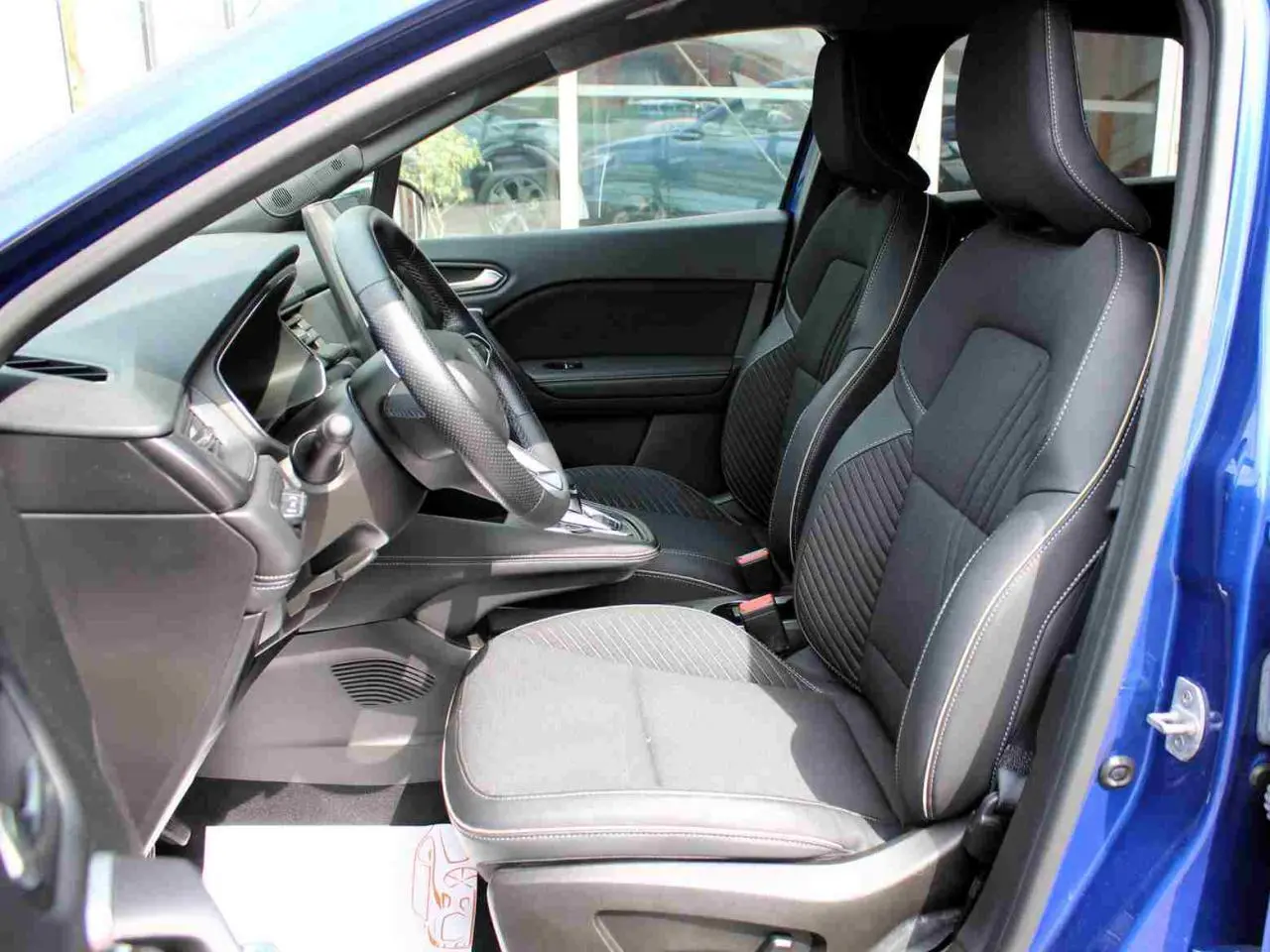 Vue intérieure côté gauche de la Renault Symbioz 2025 bleu, montrant les sièges avant et le volant textile refined.