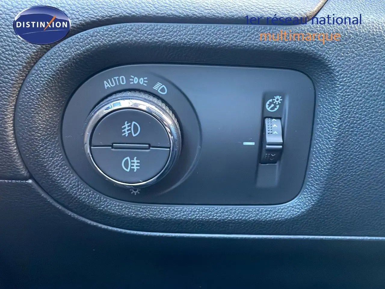 Gros plan sur le bouton de commande des phares dans l'habitacle noir de l'Opel Grandland X blanc toit noir.