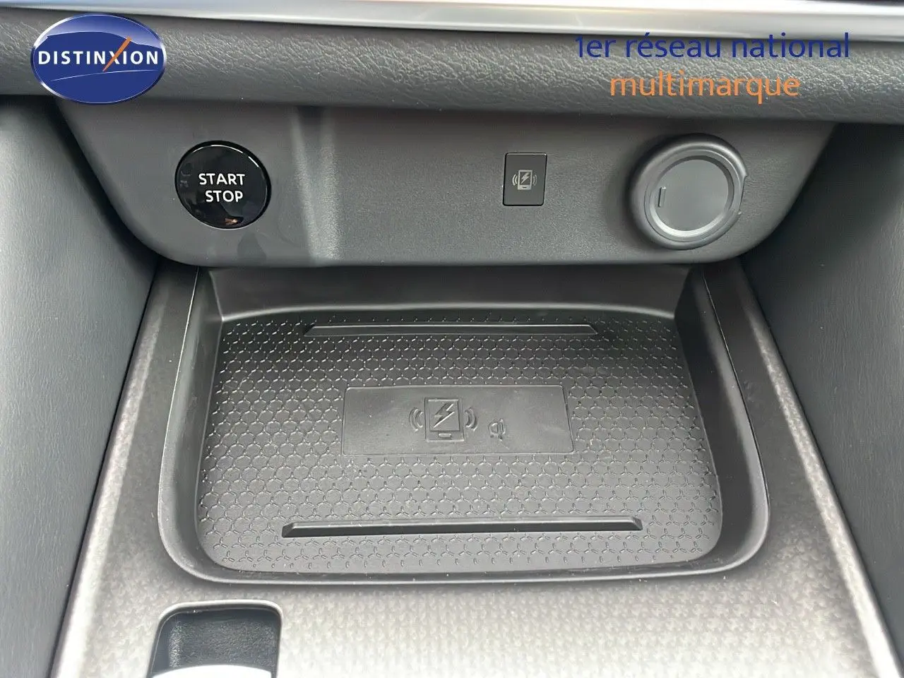 Gros plan sur la console centrale du Nissan Qashqai 2025 noir perle, montrant le bouton start/stop et le chargeur sans fil.