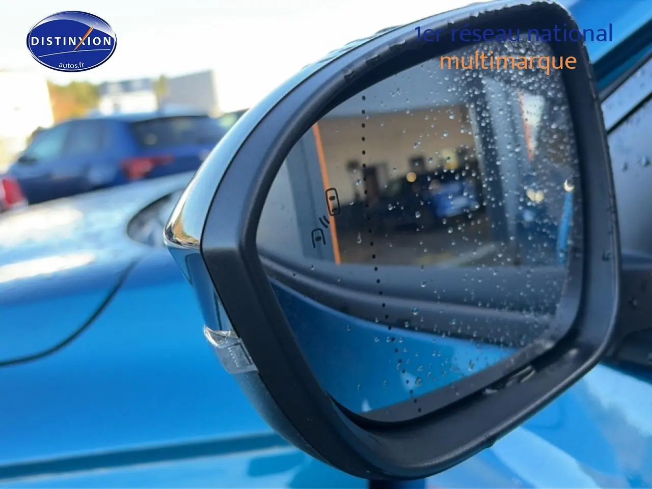 Rétroviseur extérieur droit bleu outremer de Renault Austral 2025 avec gouttes d'eau et capteur d'angle mort visible.