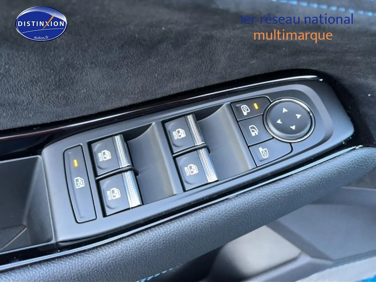 Gros plan sur les commandes des vitres électriques et rétroviseurs côté conducteur d’un Renault Austral bleu outremer.