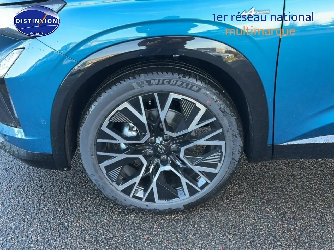 Gros plan sur la roue avant droite du Renault Austral bleu outremer avec jante alu au design géométrique.