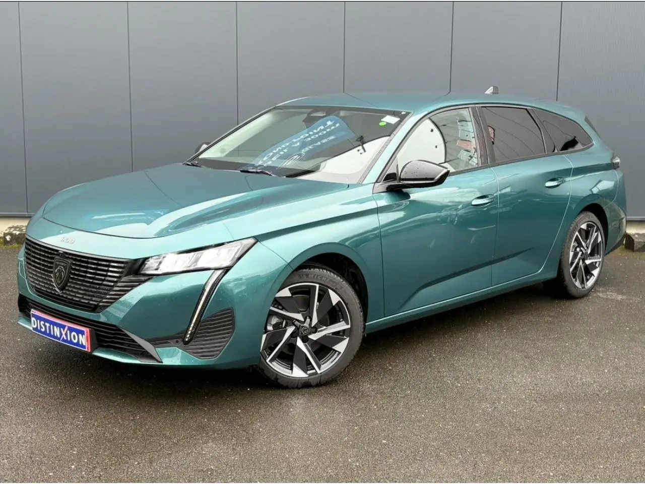 Peugeot 308 SW Hybrid bleu cuivre vue 3/4 avant droit avec jantes alliage et vitres surteintées.