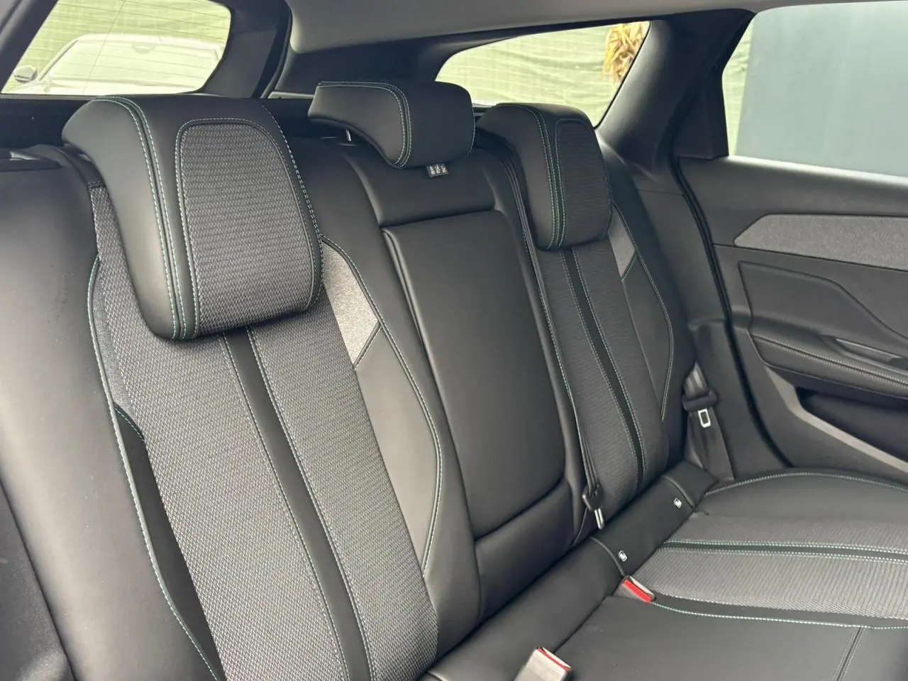 Vue intérieure des sièges arrière noirs avec surpiqûres bleues du Peugeot 308 SW Hybrid 2025 côté droit.