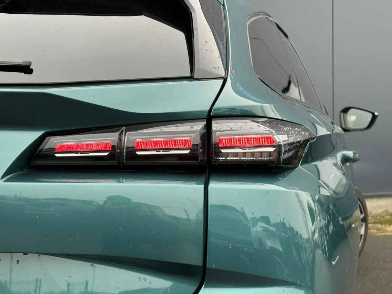 Feu arrière droit allumé d'une Peugeot 308 SW Hybrid 2025 bleu cuivre, vue en léger 3/4 arrière droit.