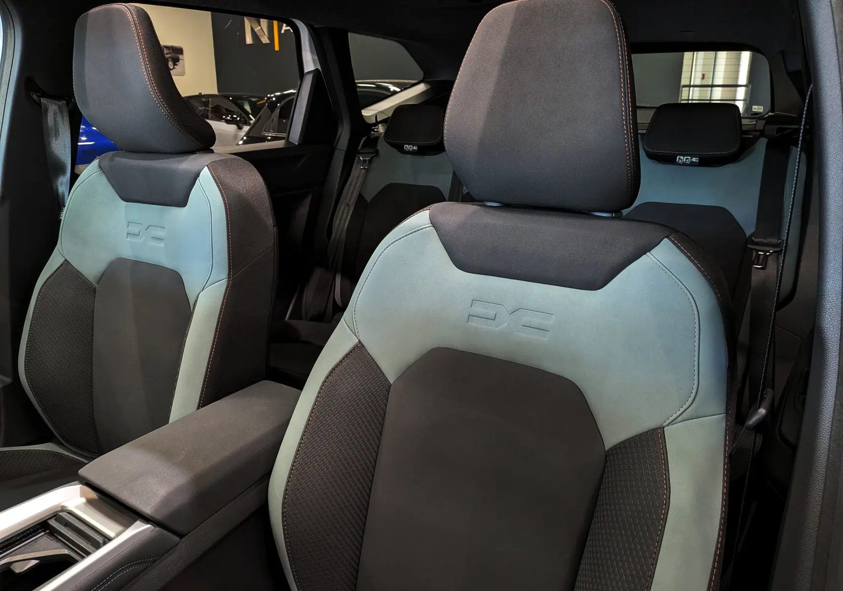 Vue rapprochée des sièges avant bicolores gris clair et noir du Dacia Bigster Hybrid-G 150 4x4, avec logo DS embossé.