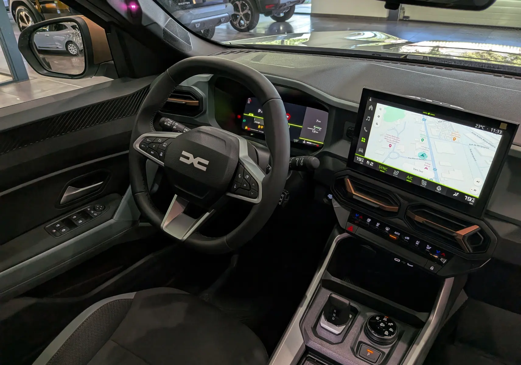 Vue intérieure côté conducteur du Dacia Bigster Hybrid-G 150 4x4 2026, avec écran tactile et volant multifonction noir.