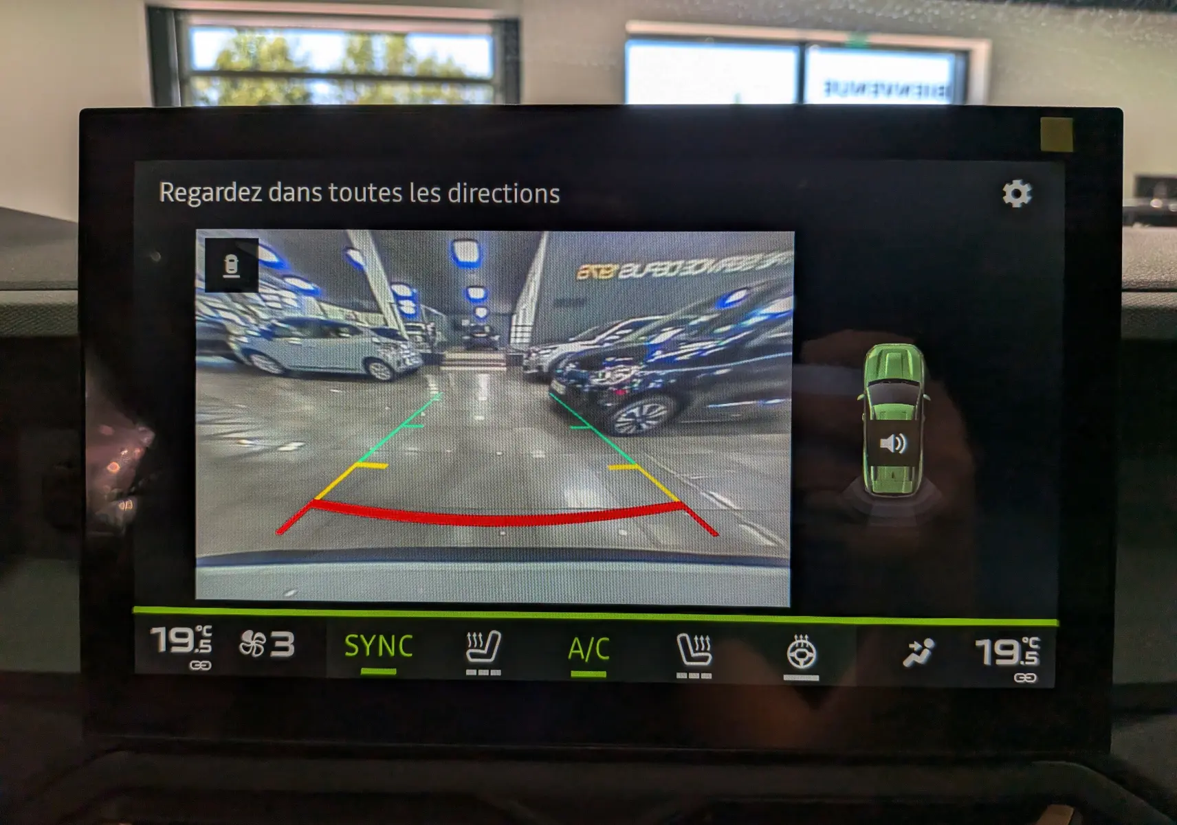 Écran multimédia montrant la caméra de recul du Dacia Bigster Hybrid-G 150 4x4 blanc Glacier en intérieur.