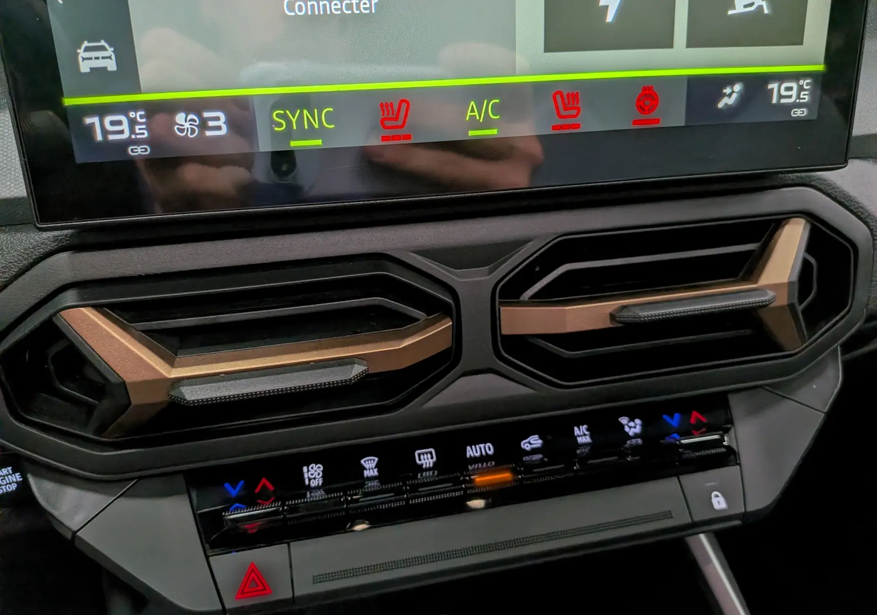 Détail du tableau de bord du Dacia Bigster Hybrid-G 150 4x4 Extrême 2026 montrant les commandes de climatisation et les aérateurs noirs et bronze.