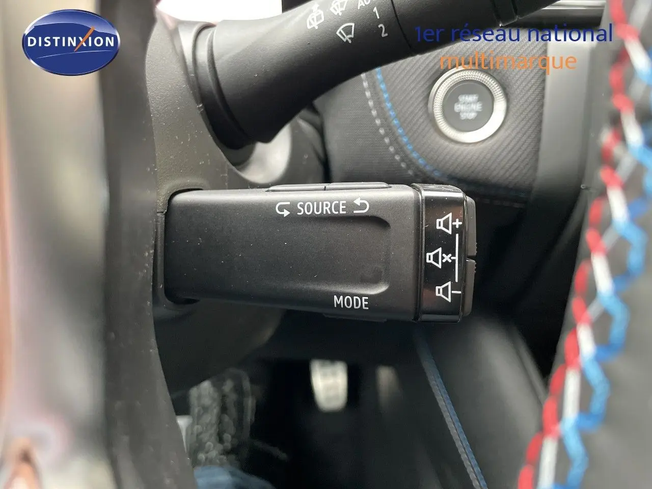 Gros plan sur la commande audio au volant du Renault Symbioz gris Rafale métal, avec bouton source et mode visibles.