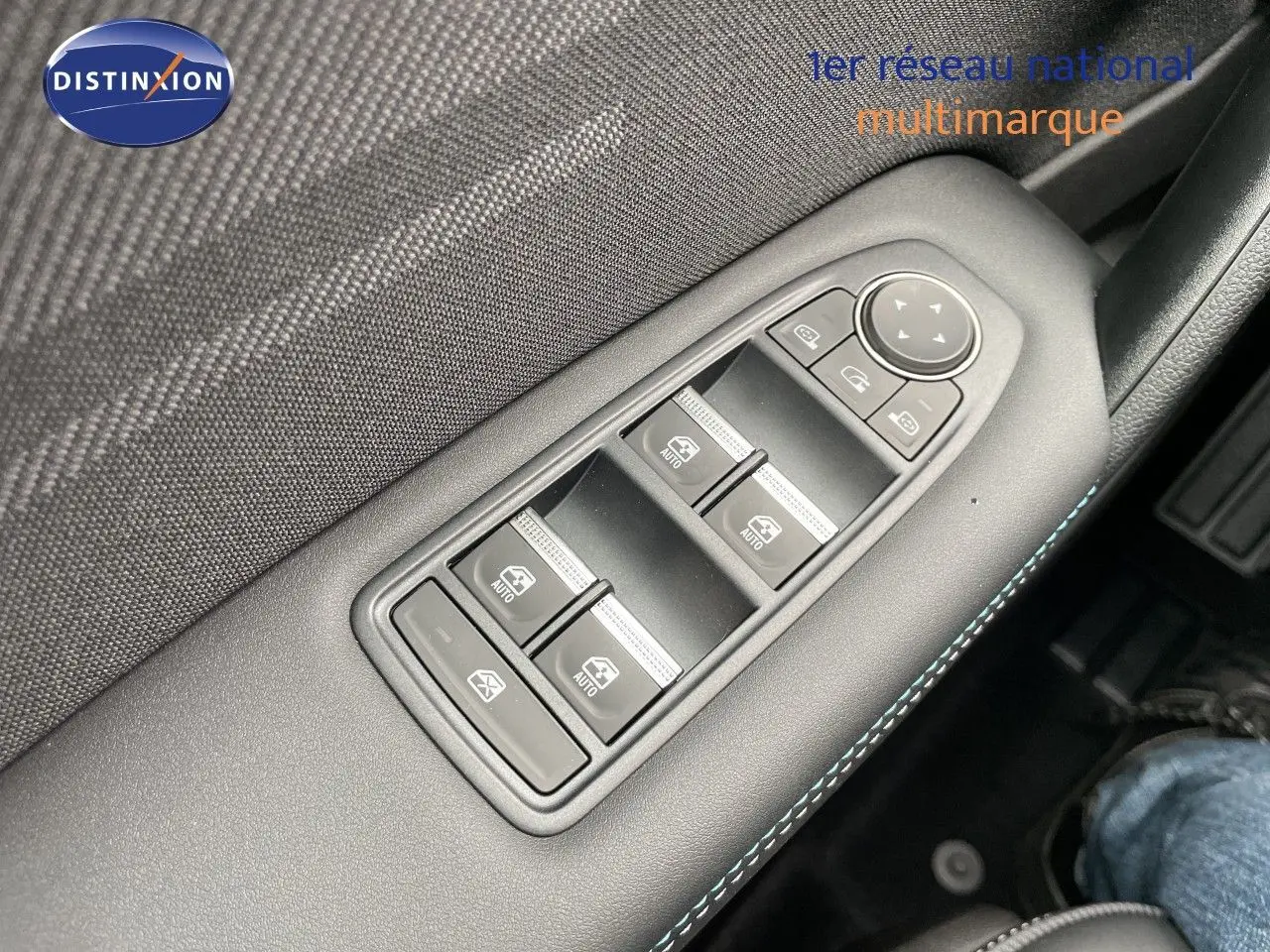 Gros plan sur les commandes des vitres électriques côté conducteur avec surpiqûres bleues, intérieur noir du Renault Symbioz gris Rafale.