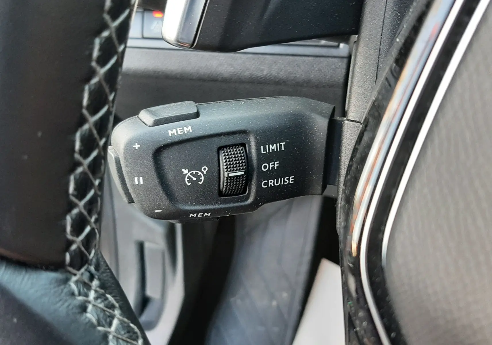 Gros plan sur la commande de régulateur de vitesse à gauche du volant d’un Peugeot 3008 gris platinium 2023.