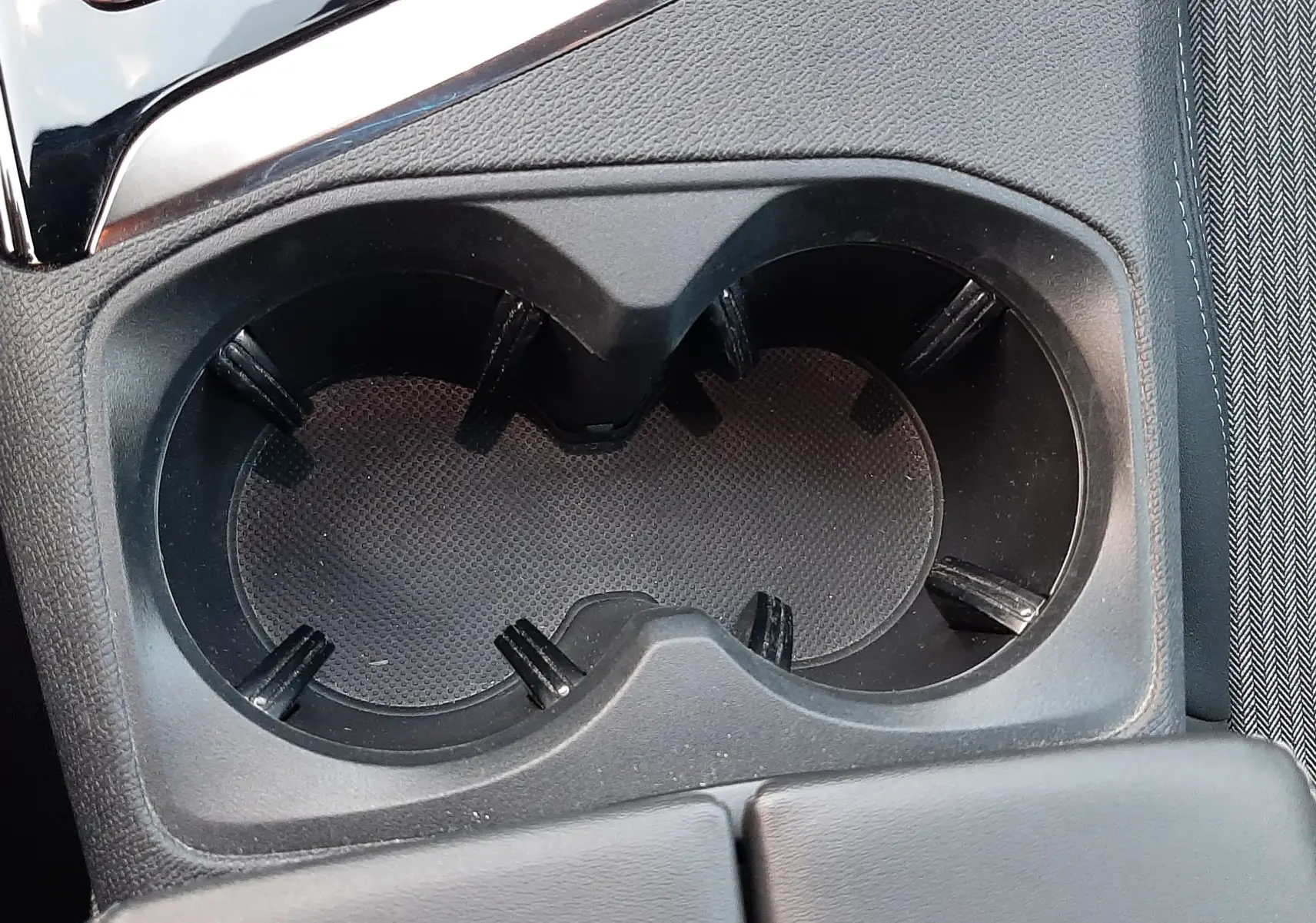 Gros plan sur les porte-gobelets noirs au centre de la console intérieure du Peugeot 3008 gris platinium 2023.
