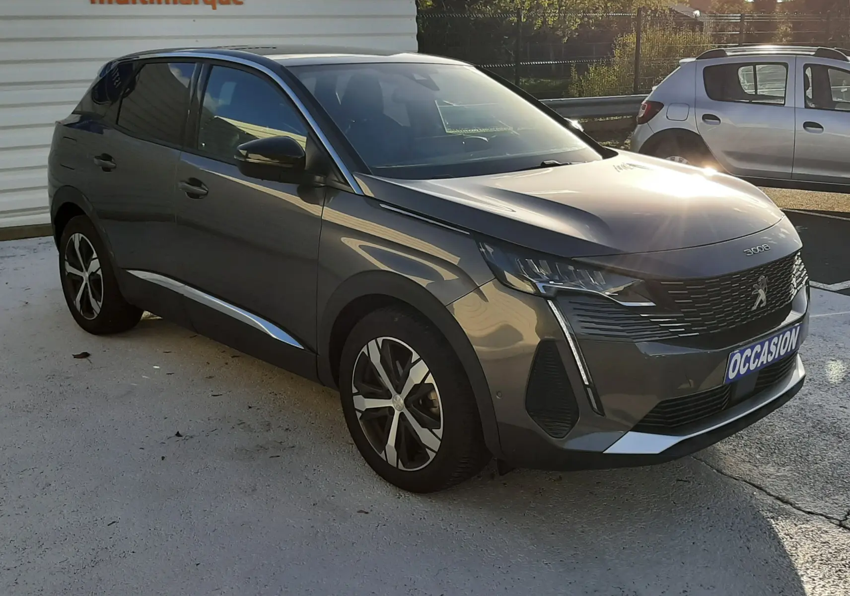 Peugeot 3008 gris platinium en 3/4 avant droit, avec jantes alliage et calandre distinctive, stationné en extérieur.