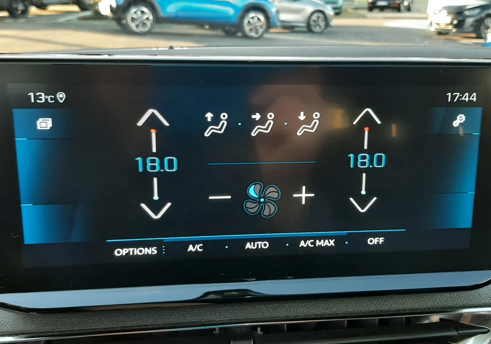 Écran tactile central du Peugeot 3008 2023 montrant la climatisation réglée à 18°C, avec aérateurs noirs en dessous.