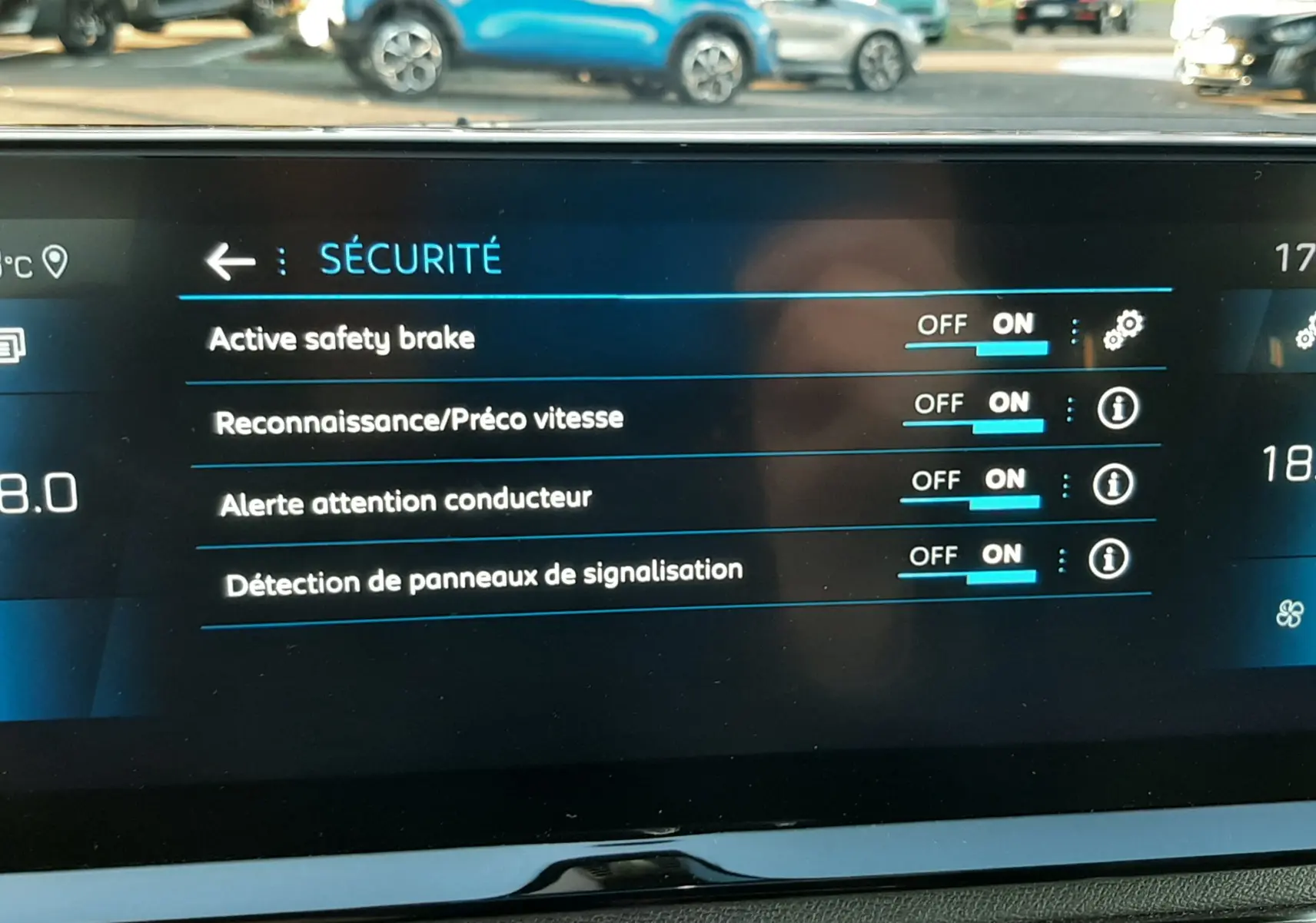 Écran tactile intérieur du Peugeot 3008 2023 montrant les réglages de sécurité activés, avec vue floue sur l'extérieur.