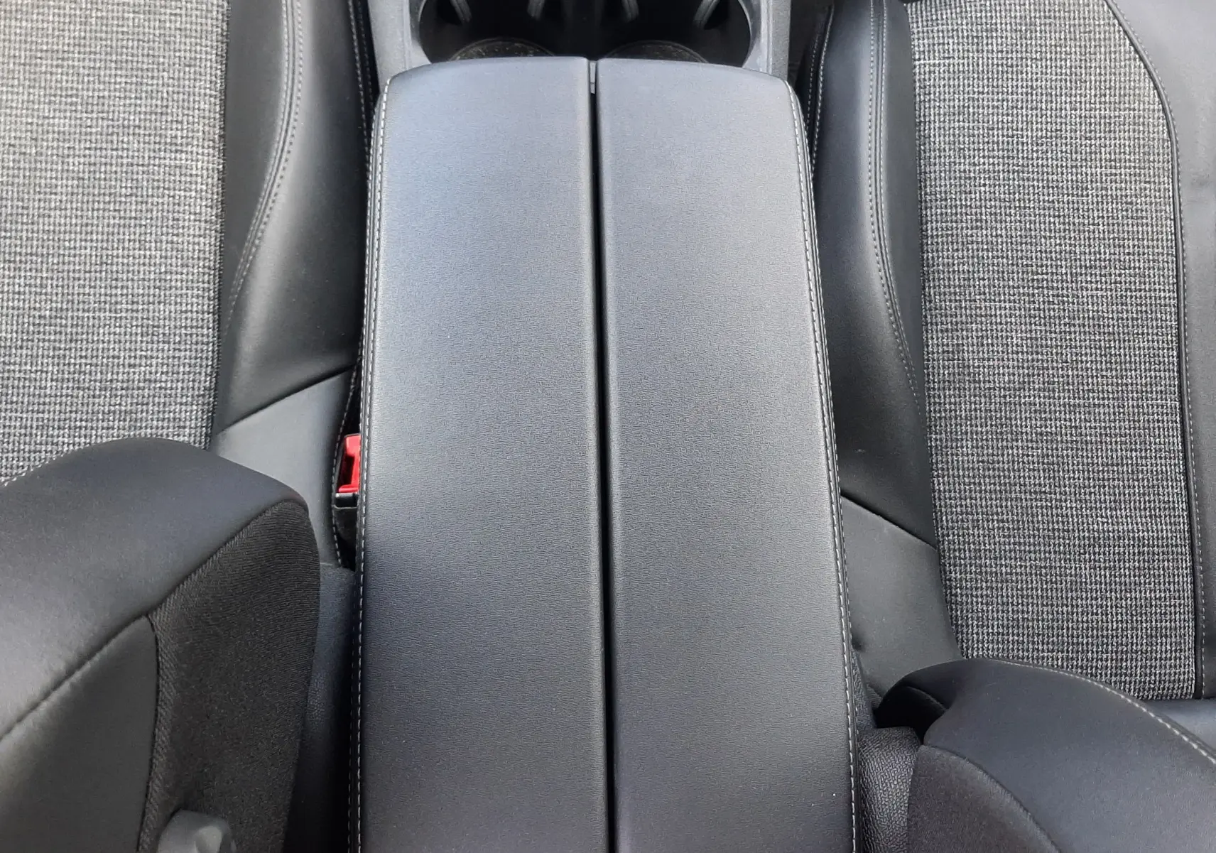 Vue plongeante sur l'accoudoir central en cuir noir et tissu gris des sièges avant du Peugeot 3008 gris 2020.