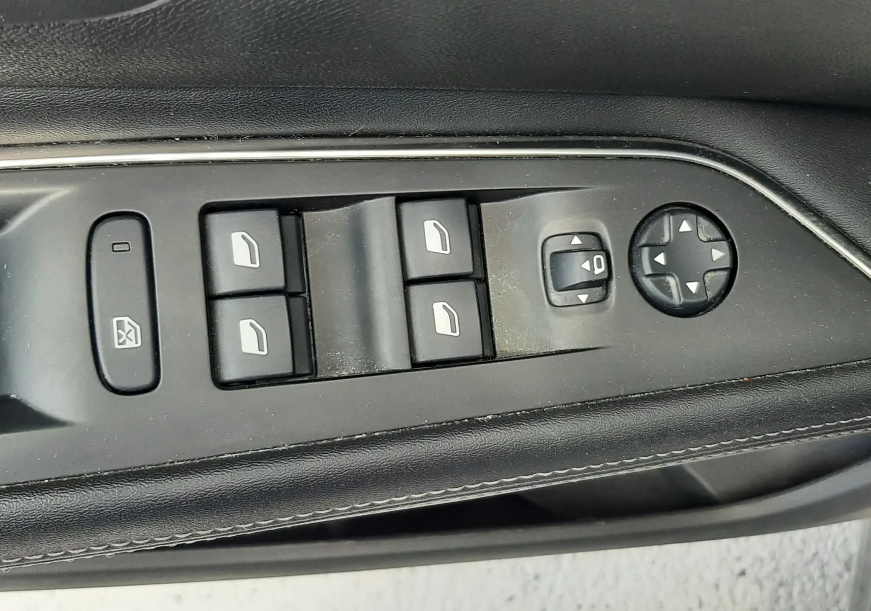Gros plan sur les commandes de lève-vitres et réglage des rétroviseurs côté conducteur d'un Peugeot 3008 gris 2020.