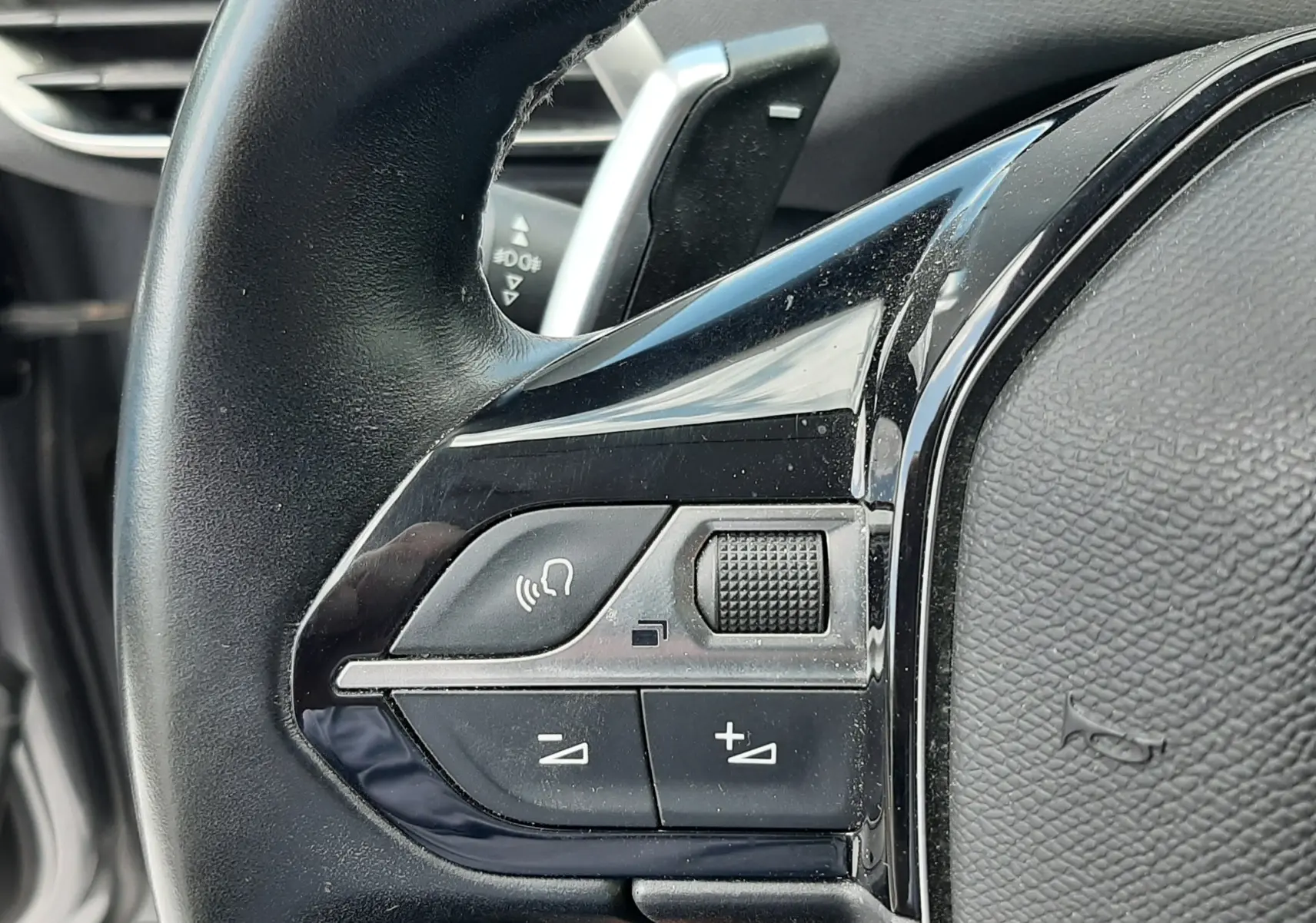 Gros plan sur les commandes au volant côté gauche d'un Peugeot 3008 gris, version 1.2 PureTech 130 Allure 2020.